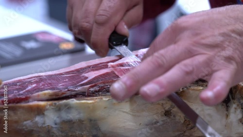 Detalle de las manos de un maestro jamonero cortando tacos de jamón. 