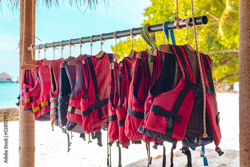 life jackets hang in a row on a hanger, the concept of a safety on the water photo
