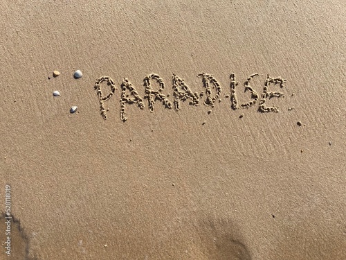 on the beach is carved with letters in the smooth sand the writing paradise