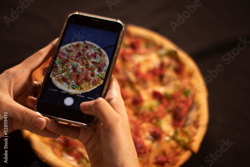 cell phone taking a picture of a pizza