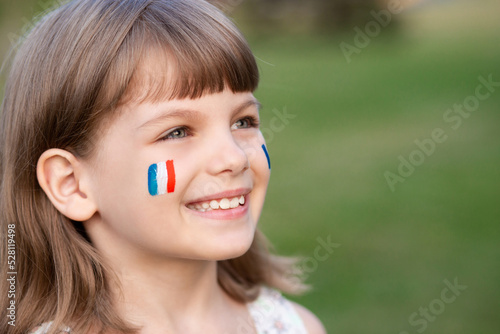 Portrait of child with painted French flag, closeup. Kid fan with blue white red flag painted on face. Education abroad. 14 July, Bastille day, main France national holiday