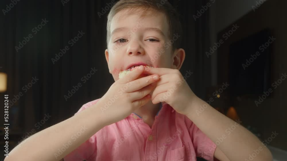 Portrait caucasian child 6 years old eats an appetizing sweet dessert donut in glaze. Cheerful little boy eats a sweet donut. Close-up of the mouth of a child eating sweet pastries. 4K Portrait caucasian child 6 years old eats an appetizing sweet dessert donut in glaze. Cheerful little boy eats a sweet donut. Close-up of the mouth of a child eating sweet pastries. 4K