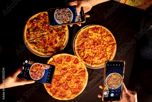 friends taking a photo of their pizza to upload to social networks
