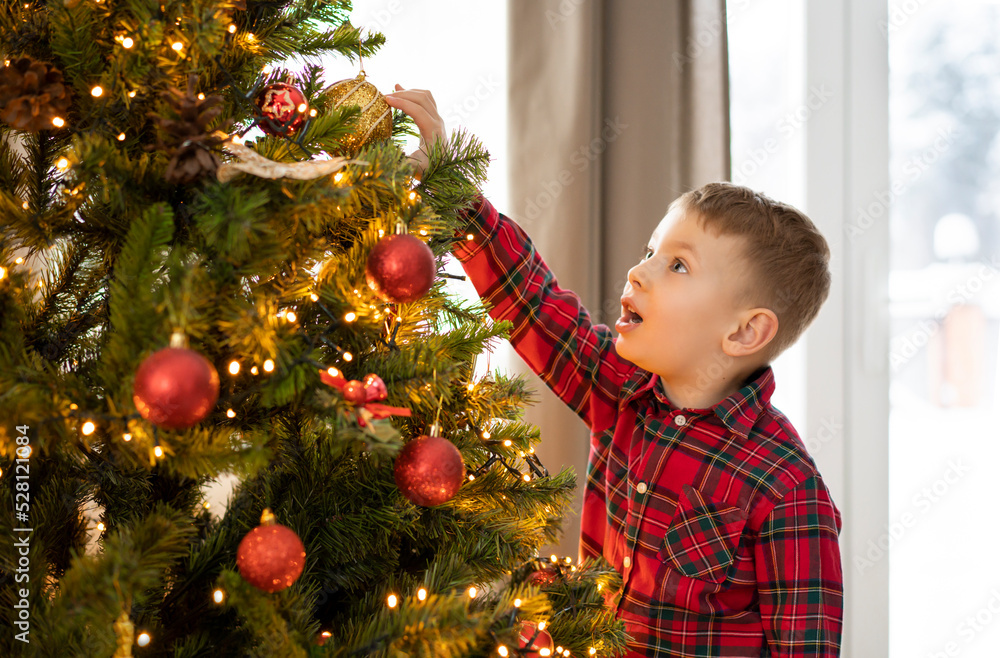 Little boy is decorating the Christmas tree