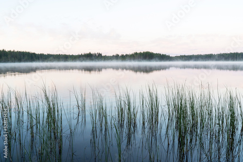 A calm summer evening by a large lake with vegetation in the background near Kuusamo, Northern Finland