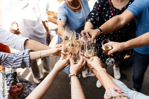 People clinking glasses of champagne against blurred background, closeup. Bokeh effect