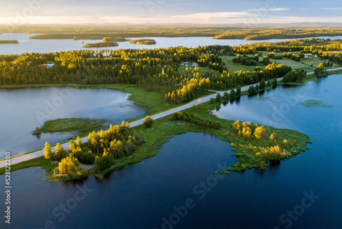 Road in the middle of lake landscape during a beautiful summery sunset in Northern Finland 