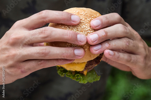 Hands holding a burger, on a restaurant table. Delicious and nutritious food.