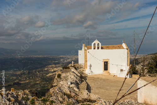 The little church of Afentis Christos on the top of Mount Giuchtas. In the background the city of Heraklion in Crete on a sunny day in December 2019 photo