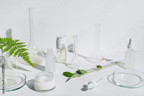 Laboratory glassware, Petri dishes and cosmetic glass bottles on white background. Natural medicine, cosmetic research, bio science, organic skin care products. Dermatology
