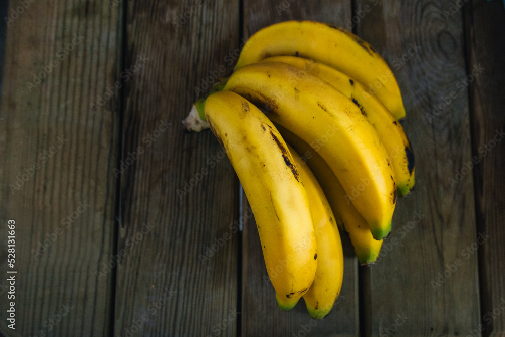 detail of several bananas on a wooden table viewed from above detail of several bananas on a wooden table viewed from above