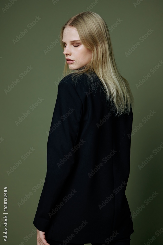 Elegant strict blonde girl turns her back to the camera looks away posing on a green background in the studio. The concept of advertising for designer brands Elegant strict blonde girl turns her back to the camera looks away posing on a green background in the studio. The concept of advertising for designer brands