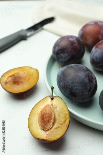 Tasty ripe plums on white table, closeup