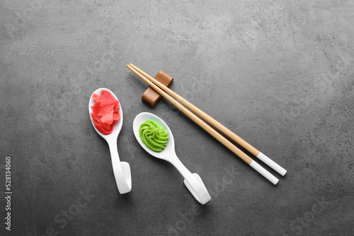 Swirl of wasabi paste, pickled ginger and chopsticks on grey table, flat lay