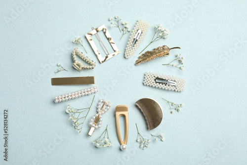 Frame of stylish hair clips and flowers on light background, flat lay photo