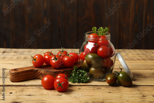 Pickling jar with fresh cherry tomatoes on wooden table