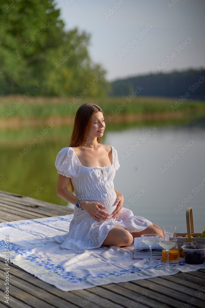 Pregnant woman reading a book, learning about parenting and pregnancy relaxing sitting on the nature in natural sunlight tone with copy space, concept motherhood education, pregnant woman activity.