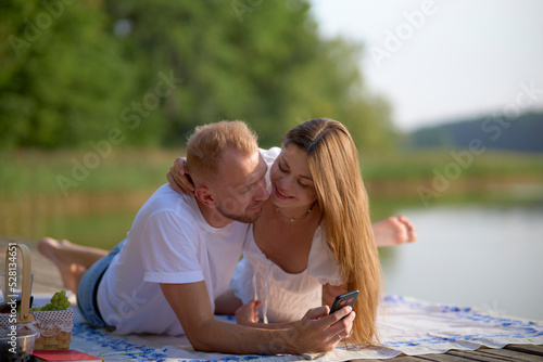 A couple in love are having a picnic in nature by the lake. Hugging, kissing, having a good time. The concept of a happy family.