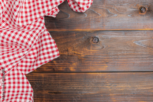 Checkered red and white on an old wooden background with copy space, top view. Fabric texture background. The texture of the cotton fabric. With copy space for design menu of food for the restaurant.
