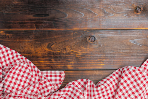Fabric red and white cover on the table. Flat lay, top view. Background of menu for the restaurant, copy space. Checkered red and white tablecloth on an old wooden brown background with copy space.
