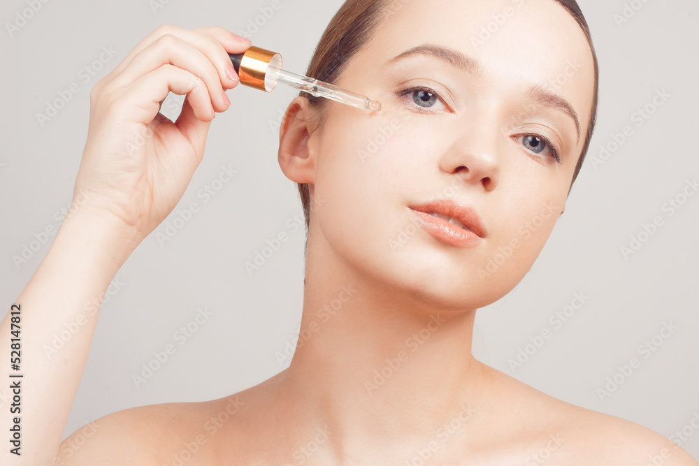 Girl on a white background skin care, oil, serum with a pipette on her face Girl on a white background skin care, oil, serum with a pipette on her face