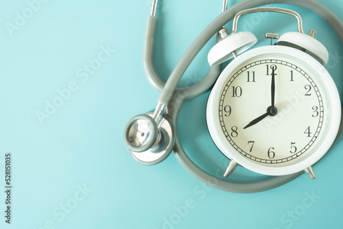 Top view of stethoscope and alarm clock on the green table background, schedule to check up healthy concept © tatomm