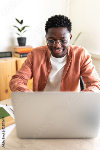 African American male college student studying at home using laptop. Vertical image.