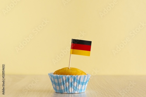 Homemade cupcake with Germany flag on beige wood background. Holiday Independence Day. Germany flag decorates cakes. photo