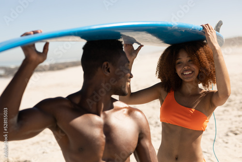 Mixed race couple holding surf boards on the beach