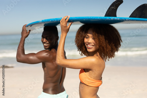 Mixed race couple holding surf boards on the beach