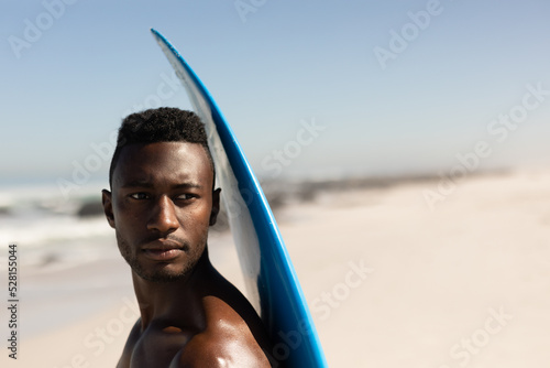 African American man holding surf board on the beach #528155044