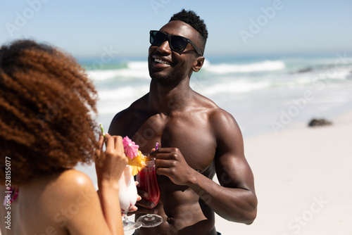Mixed race couple drinking cocktails on the beach
