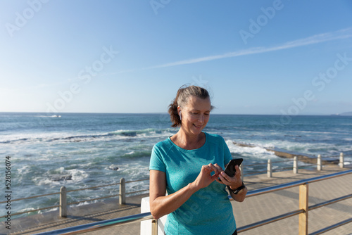 Female jogger using mobile phone on seaside