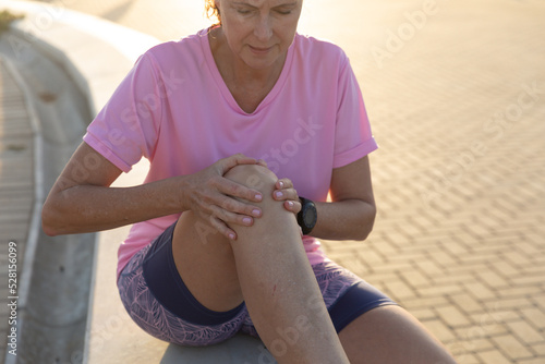 Jogger woman holding legs on seaside
