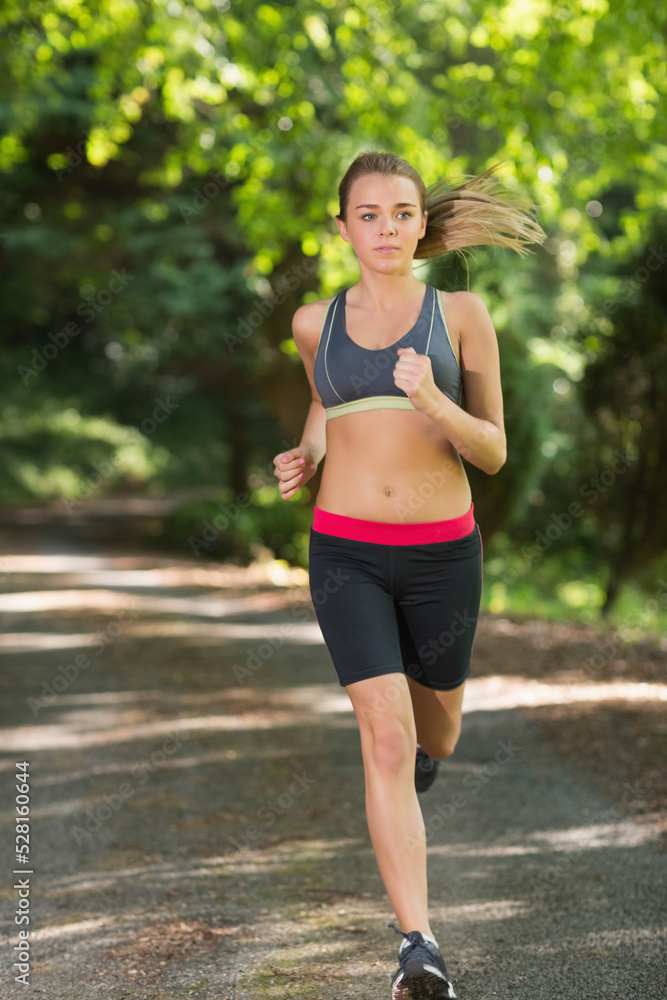 young woman jogging on footpath in park young woman jogging on footpath in park