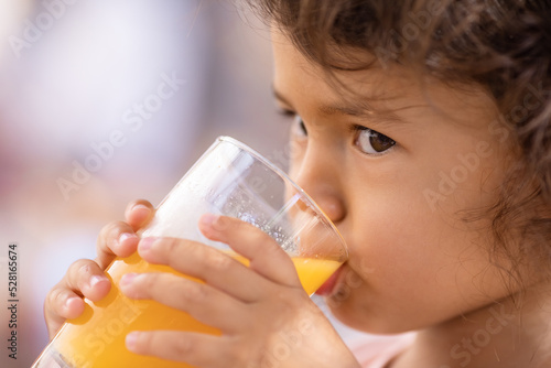Little toddler girl drinking orange juice at resort in Mexico  childhood memories and summer vacation concept