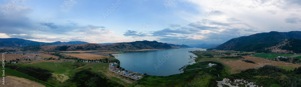 Aerial View of Okanagan Lake with farm lands and mountain landscape. Cloudy Sunset Sky. Near Vernon, British Columbia, Canada. Nature Panorama Background