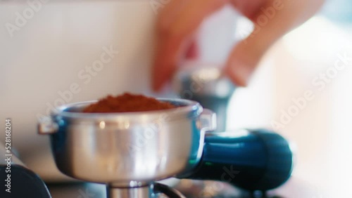 Barista prepares espresso and tempers coffee in portafilter photo