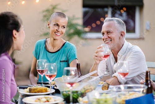 Mature man drinking a glass of wine together with friends during a dinner in summer