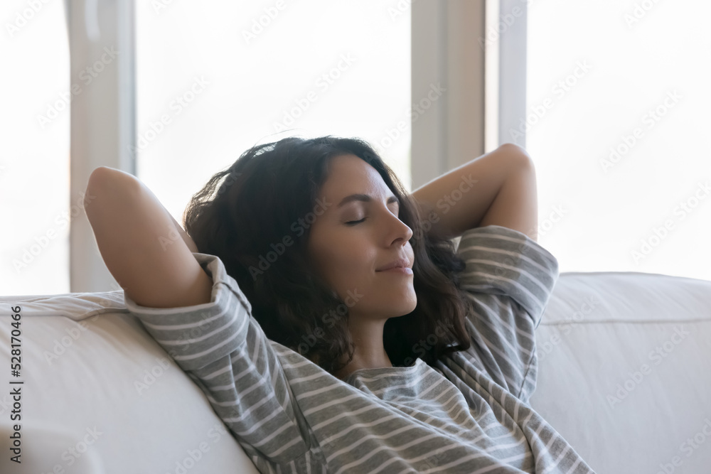 Beautiful woman relax on sofa with hands behind head, close up, spend carefree weekend leisure alone, enjoy silence, air conditioning system inside, quiet house appliances at home. Daydreams concept Beautiful woman relax on sofa with hands behind head, close up, spend carefree weekend leisure alone, enjoy silence, air conditioning system inside, quiet house appliances at home. Daydreams concept