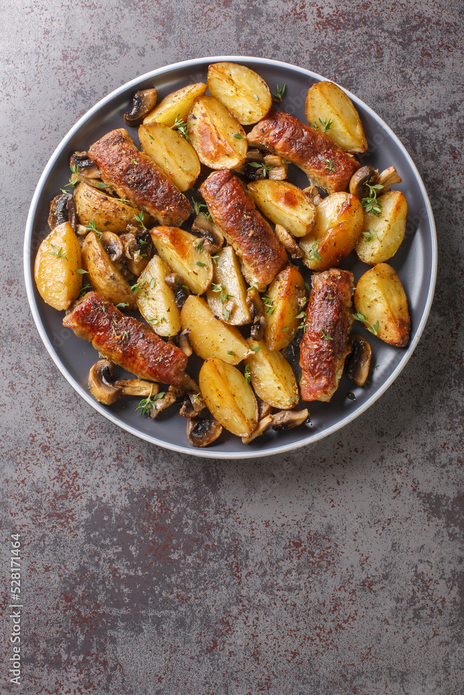 Roast beef rolls with baked potato wedges and mushrooms served on plate closeup on the table. Vertical top view from above Roast beef rolls with baked potato wedges and mushrooms served on plate closeup on the table. Vertical top view from above