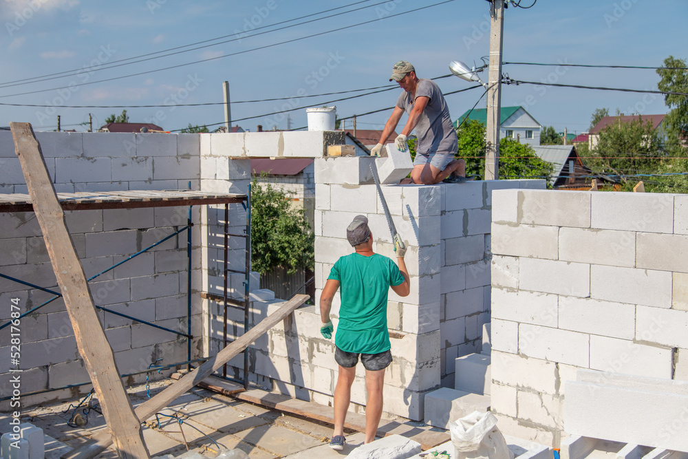 A worker builds the walls of a house from aerated concrete bricks. A worker builds the walls of a house from aerated concrete bricks.