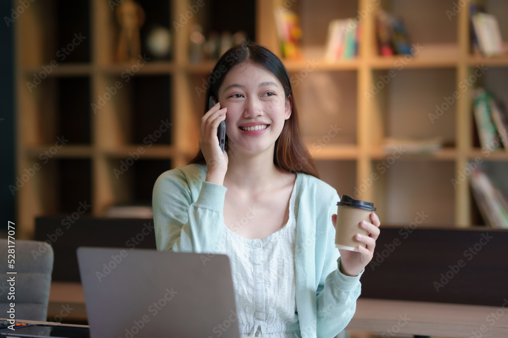 Beautiful Asian business woman chatting on the phone with customer and working on her laptop and taking note enthusiastically and happily in the office. Beautiful Asian business woman chatting on the phone with customer and working on her laptop and taking note enthusiastically and happily in the office.