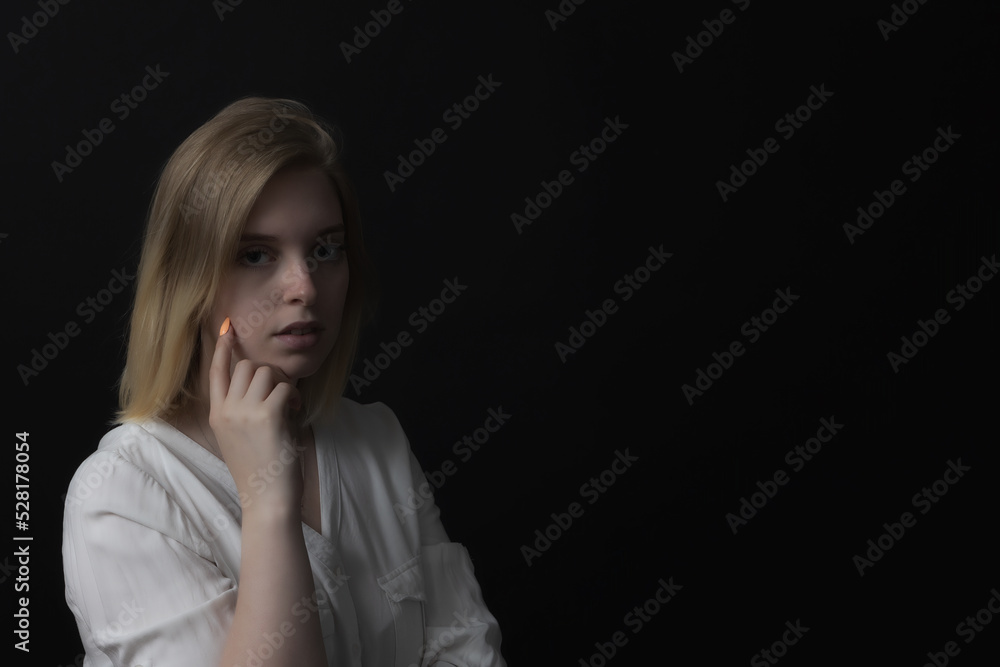 Low key portrait of serious young woman looking at the camera. Horizontally. Low key portrait of serious young woman looking at the camera. Horizontally.