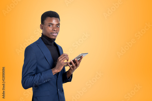 African businessman with tablet in hands, copy space yellow background