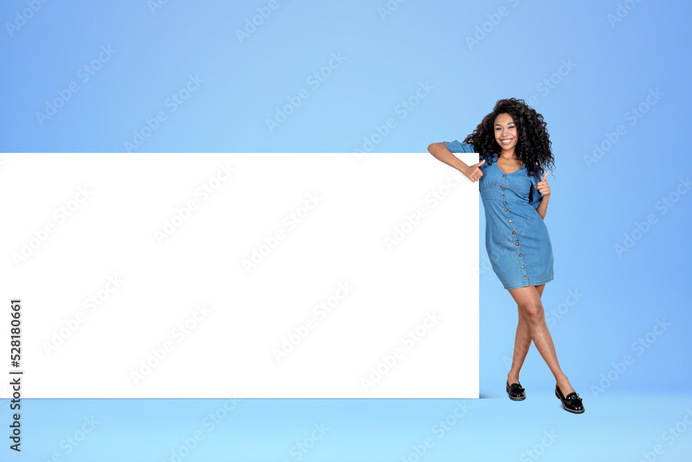 African woman shows thumb up near mockup canvas on blue background African woman shows thumb up near mockup canvas on blue background
