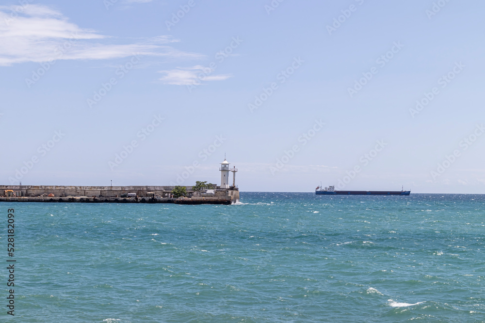 lighthouse on the pier and cargo ship