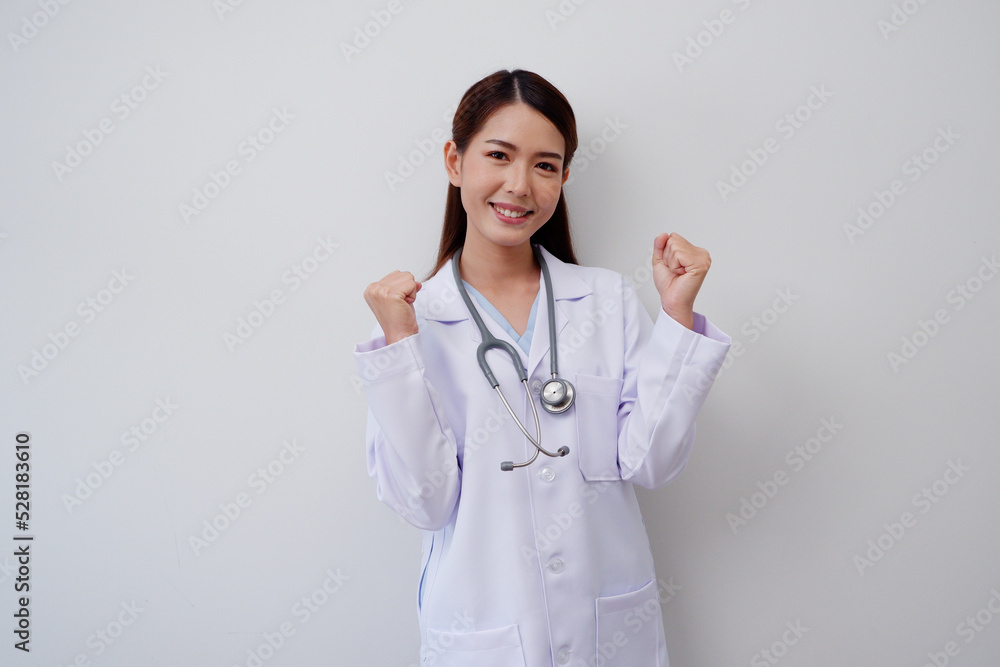 Beautiful Asian female doctor standing smiling happy Show winning and successful gestures. with a stethoscope on the shoulder wearing a white medical gown. Beautiful Asian female doctor standing smiling happy Show winning and successful gestures. with a stethoscope on the shoulder wearing a white medical gown.