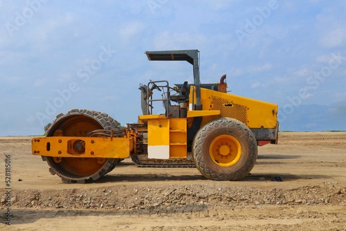 road roller with yellow color, on construction site and sky background