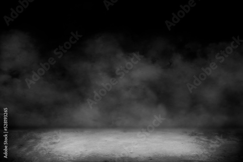 Fotografia Concrete floor with smoke or fog in dark room with spotlight